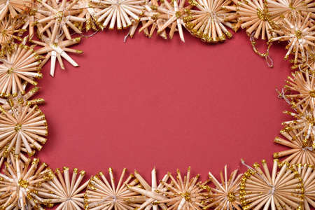 Christmas background with golden straw stars on a red background. greeting card with blank spaceの写真素材