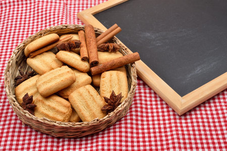Biscuits for Christmas with cinnamon and anise near a blank blackboard on a red and white tablecloth