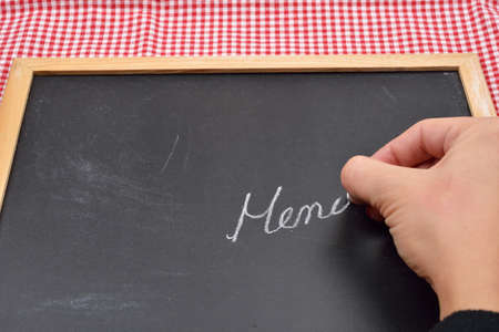 Close up of a female hand writing on a blackboard the menu for the restaurant, with copy space for textの写真素材