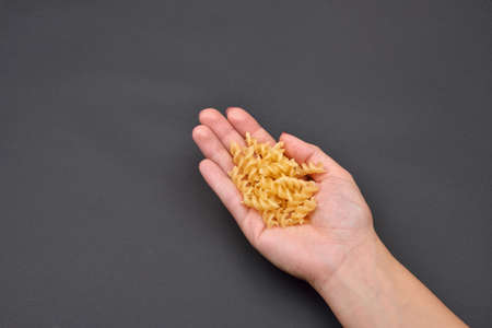 Hand of a woman holding a pile of fresh fusilli isolated on black background. Meal preparation. Cooking. Foodの写真素材