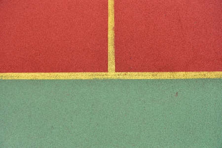 Detail of crossed yellow lines on football playground. Detail of lines in a soccer field made from red and green granule rubberの写真素材