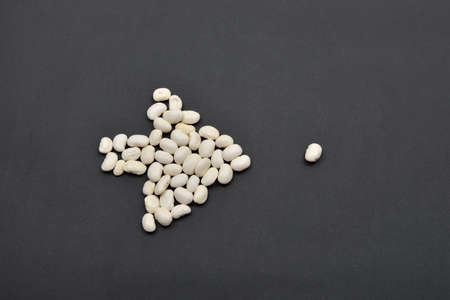 Arrow made from white beans, pointing the way by a bean on black background. Food vegan, vegetarian. Healthy foodの写真素材