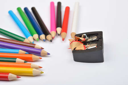 Close up of little colored pencils with black pencil sharpener and pencils shavings on it on white background. Selective focusの写真素材