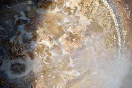 Boiling meat for a hungarian goulash cooked in a stew-pot on an open fire, on a summer sunny day. Outdoor. Shadowsの写真素材