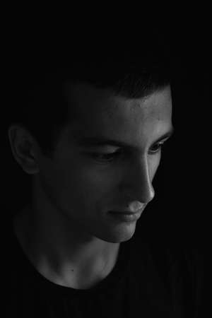 Portrait of sad and serious teenager looking to the side. Concept teenage problems. Black and white. Lights and shadowsの写真素材