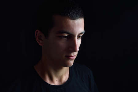 Portrait of smiling and thinking teenager looking to the side in a studio. Lights and shadowsの写真素材