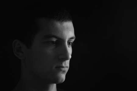 Portrait of sad and serious teenager looking to the side. Concept teenage problems. Black and white. Lights and shadowsの写真素材