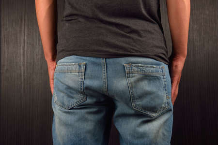 Back of young man wearing grey blank t-shirt, standing in a studio. Clothing design conceptの写真素材