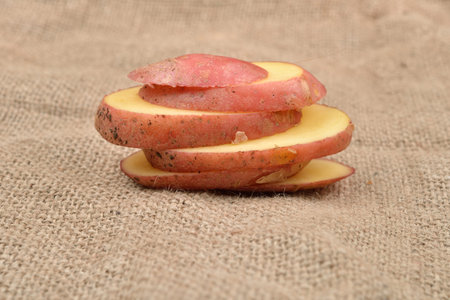 New fresh red potatoes cute in slices on jute background. Concept of healthy food, bio from countrysideの写真素材