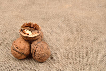 Whole and broken walnuts on jute background. Healthy food. Selective focus. Copy spaceの写真素材