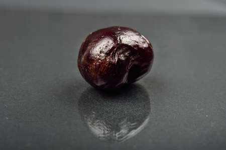 Close up of image of rotten red cherry fruit on reflective black background. Selective focus.の写真素材