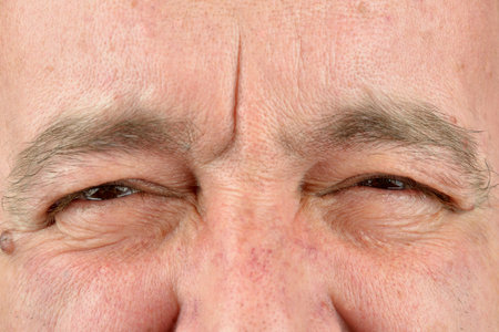 Close up picture of brown mature man eye. He is trying to read something and he is frowning his lookの写真素材