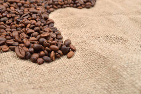 Vintage photo, roasted coffee beans on brown jute background. Morning pleasure. Still life. Selective focus. Copy spaceの写真素材