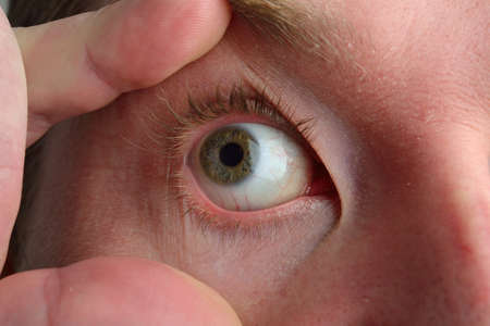 Close up picture of beautiful blue man eye, man trying to open his eyelids with his fingers. Foft focusの写真素材