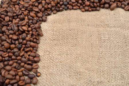Vintage photo, roasted coffee beans on brown jute background. Morning pleasure. Still life. Selective focus. Copy spaceの写真素材
