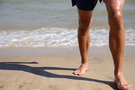 Shot of a pair of wet feet standing on a sandy beach. Enjoying the warm water and the hot sun.の写真素材