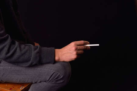 Close up of a teenager hand holding a cigarette. Studio photo. Harmful smoking concept. Unhealthy habits.の写真素材