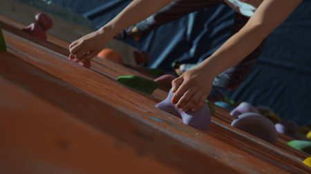 hands of a athletic woman hold on to artificial stones in the bouldering wallの写真素材