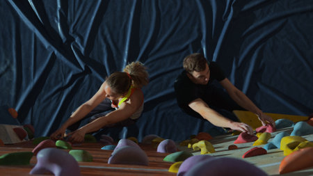 Two athletes, a man and a woman, climb a wall together for a climbing wallの写真素材