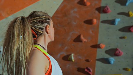 a female climber stands near the artificial wall of the climbing wallの写真素材