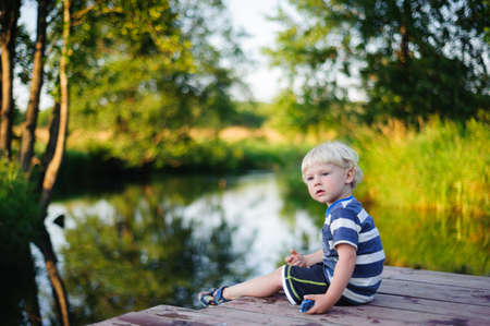 Young boy sitting on the river bridgeの写真素材
