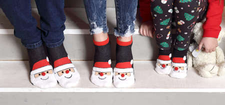 Feet in wool socks near fireplace in winter. Closeup image of family in warm knitted socks lying next to fireplaceの写真素材