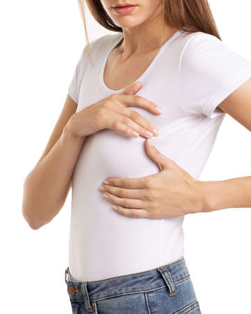 Woman hand checking lumps on her breast for signs of breast cancer on gray background. Healthcare concept.の写真素材