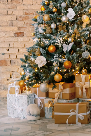 Christmas, New Year interior with red brick wall background, decorated fir tree with garlands and balls. Holiday decorated room with chairの写真素材