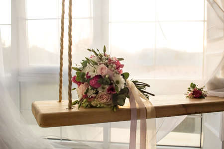 Wedding background: flowers bouquet on indoor swing on sunny romantic windowの写真素材