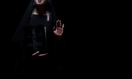 Witch holding a spell magic book with pentagram symbol standing. Halloween, black magic concept mockup.の写真素材