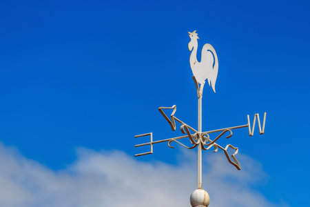 weather vane with North South East West compass points against clear blue sky