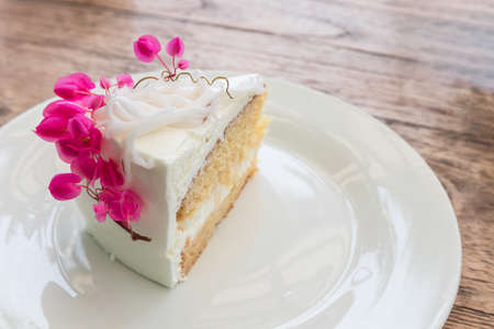 Coconut cake decorated with pink flowers on white plateの写真素材