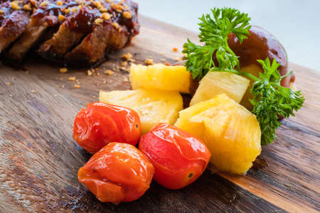 Roast tomatoes, pineapple slice and mashed potatoes on wood plate.の写真素材