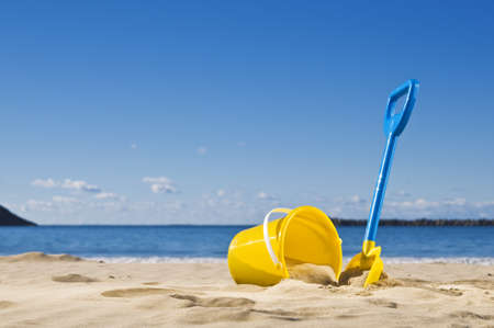 Spade and bucket by the water's edge, ready to build a sandcastle.の写真素材