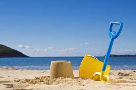 Shot of the beach on a sunny day, with a spade and bucket in foreground.の写真素材