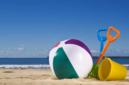 Day at the beach with a beach ball, spade and bucket in the foreground. の写真素材