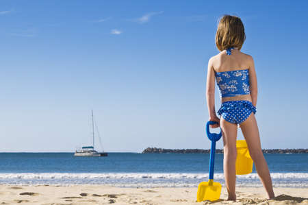 Young child with spade and bucket standing on the beach.の写真素材