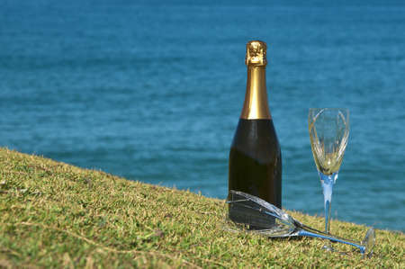 Champagne and glasses on the top of a headland overlooking the ocean の写真素材