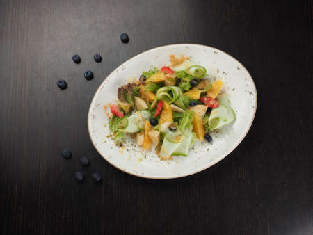 A plate of fruit cut into pieces. Tangerines, banana, apple, pear, berries in a plate. Sweet treats for dessert. Healthy food.の写真素材