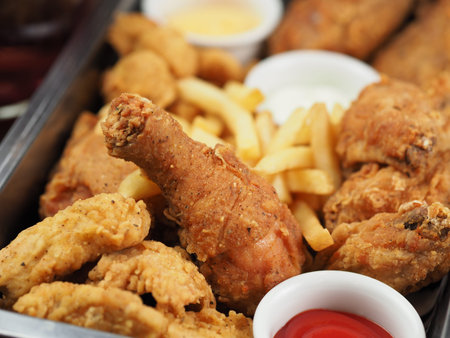 Chicken nuggets, french fries and sauce on dark wooden background. Fried nuggets and potato with...