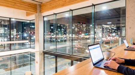 Businessman working on laptop computer in coffee shop with blurred city background.の素材