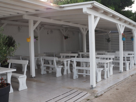 Restaurant with white tables and chairs in the shade of trees.の写真素材