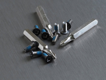 Screws and replacement bits for a screwdriver on a gray metal background close-up