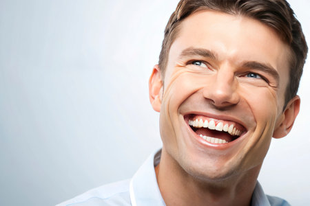 Close up portrait of a happy young man laughing against white background.の素材