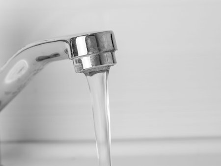 Faucet with flowing water, close up. Selective focus.