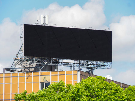 Large Black Digital Billboard on Metal Structure Above Urban Building Under Blue Skyの写真素材