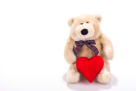 Teddy bear sitting with valentine heart isolated on whiteの写真素材