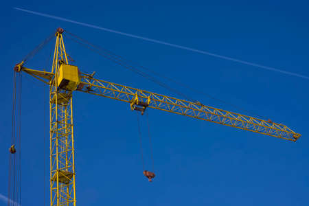 Top of tower crane against blue sky with jet traceの写真素材