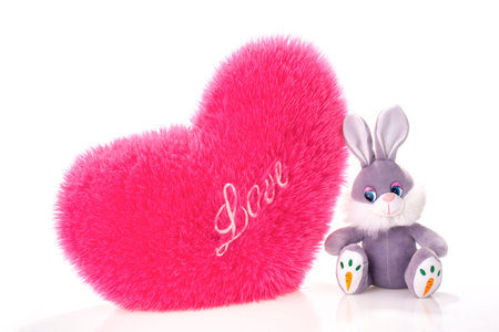 Toy hare and heart-shaped pillow isolated on whiteの写真素材