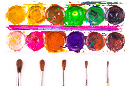 Set of used watercolour paints and paintbrushes on white